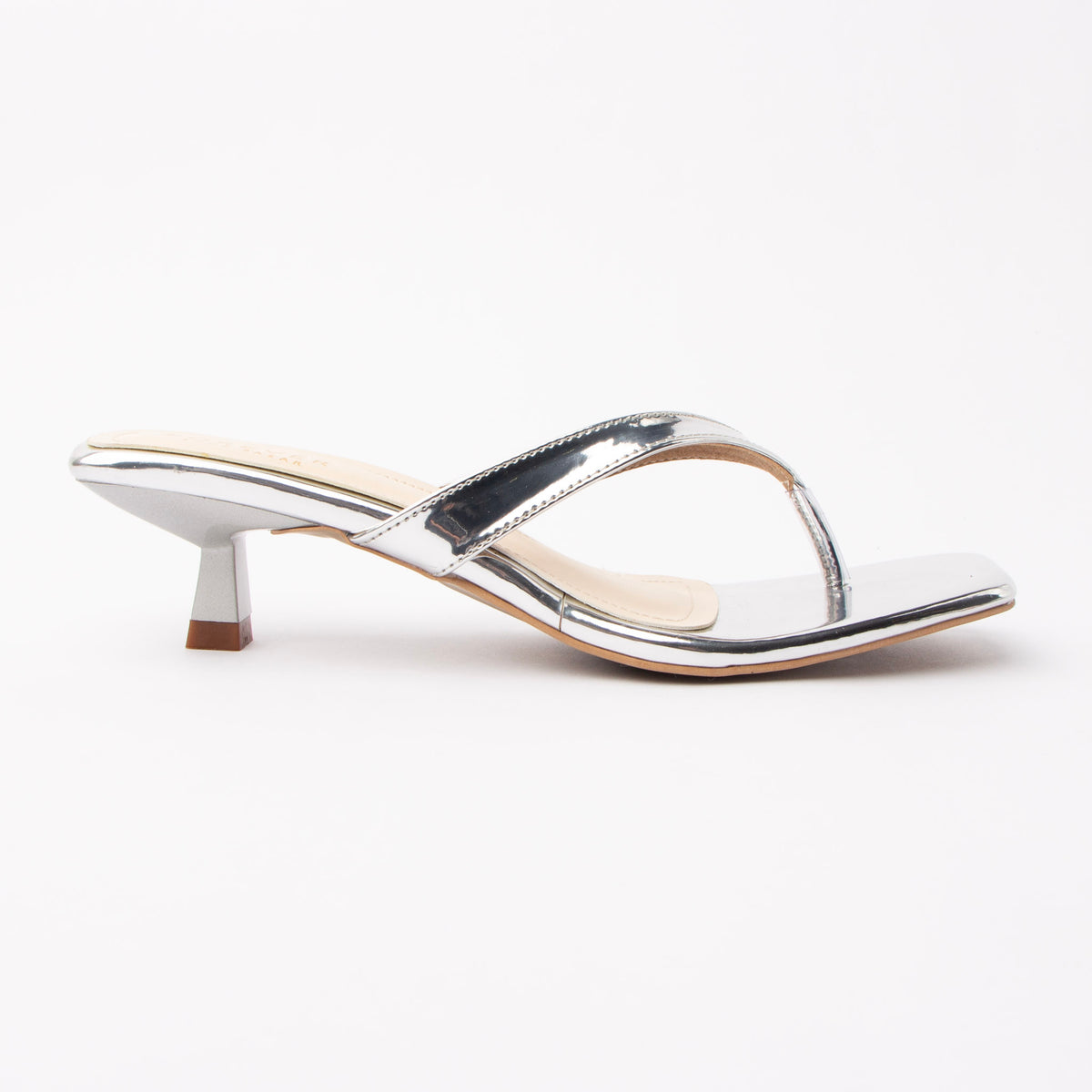 Silver toe-post kitten heel mules for women, side view of the twisted vamp band, squared-off open toe and slim kitten heel