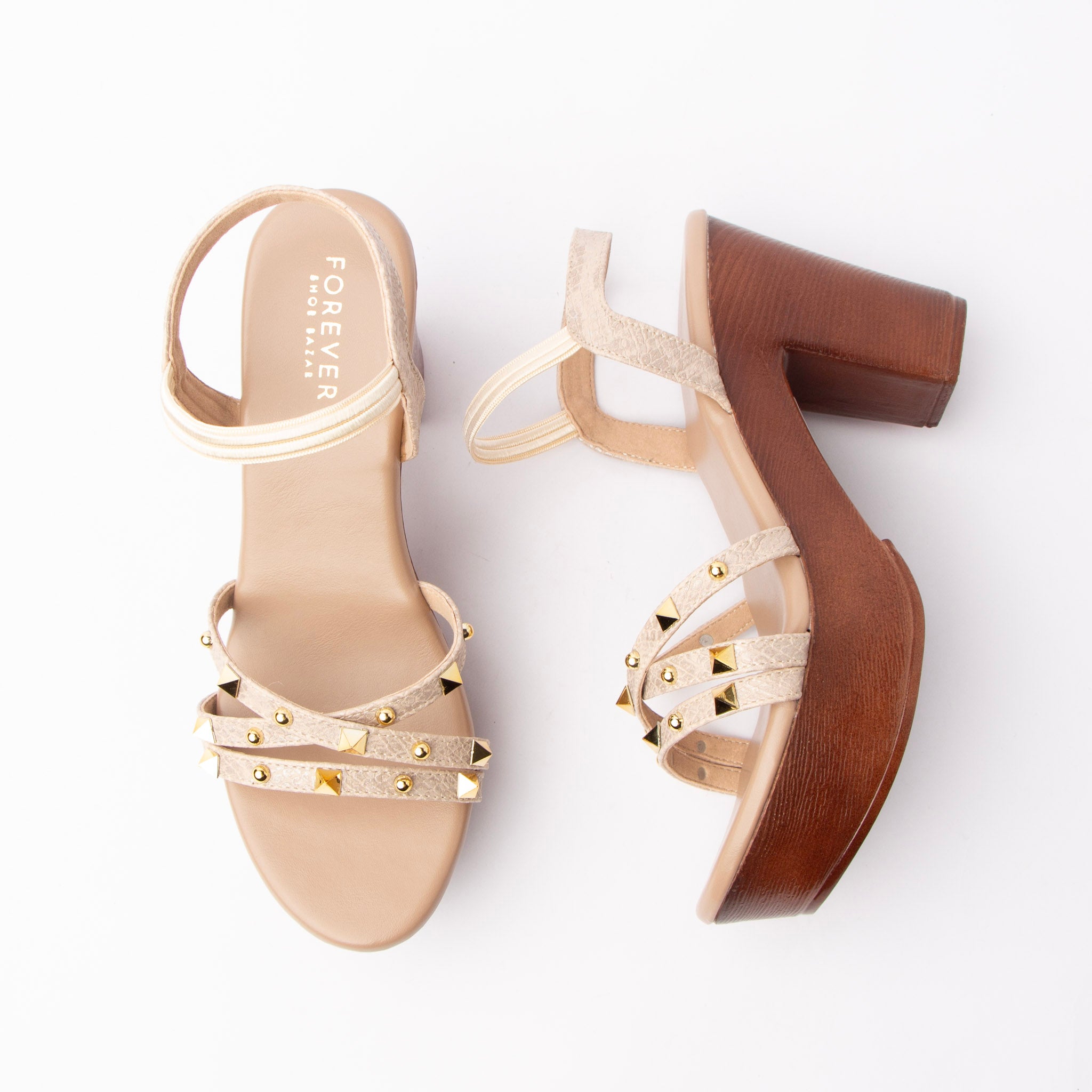 Beige studded platform heels for women, three slim cream croc-embossed straps cross the vamp under a scatter of gold pyramid and round dome studs, held by an elasticated cream ankle loop, over a tan leather-look footbed set on a wood-grain platform and matching wood-grain block heel