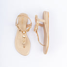Gold flat sandals for women, gold seashell and starfish charms clustered with pearls along the T-bar, a slim toe post below and a fine ankle strap closed by a small gold buckle, on a cushioned metallic footbed