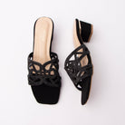 Black cut out block heel mules for women, one wide scalloped vamp band in black laser-cut pu, every cutout edge outlined in fine jet-black micro-crystals so the sparkle reads tonal rather than contrasting, set over a nude-lined cushioned footbed with a gold heel-seat logo, plain open back and a squat black-covered block heel