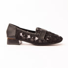 Black lace loafers for women, black floral guipure lace embroidered onto sheer black mesh so the daisy motifs read as raised texture, banded across the vamp with smooth black leather, on a low block heel ringed in gold over a contrast-stitched footbed