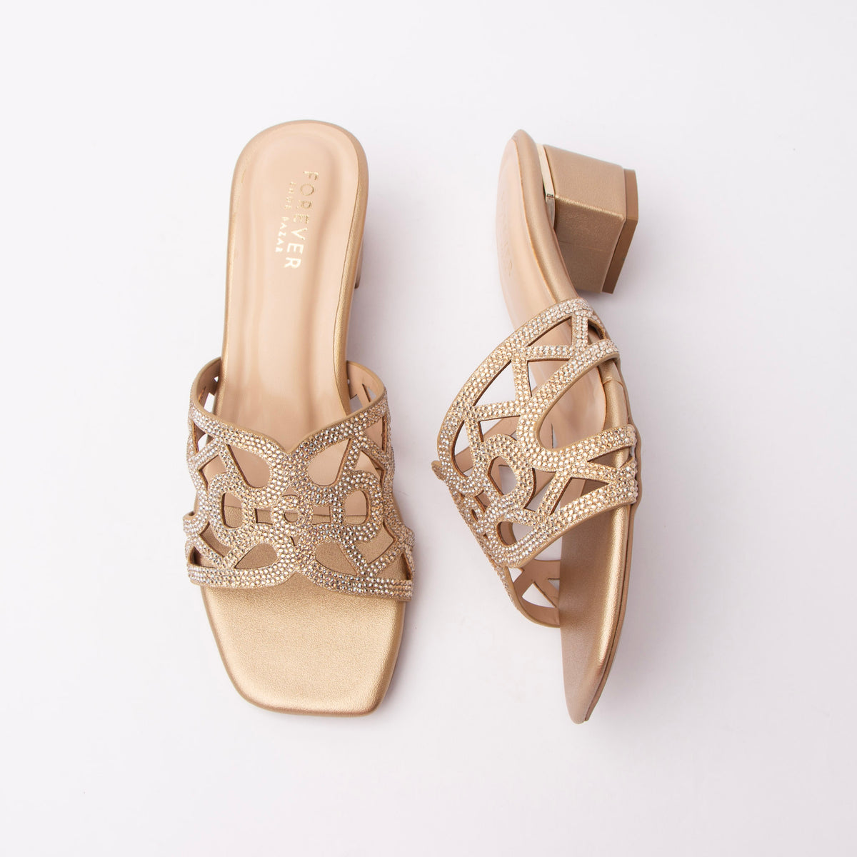 Gold cut out block heel mules for women, a warm light-gold metallic vamp cut into a butterfly-loop lattice and paved with champagne-tone crystals, sitting on a tonal gold footbed, with a matching gold-wrapped low block heel and an open back