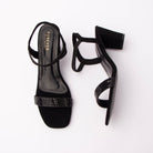 Black embellished block heel sandals for women, a single broad toe band tiled with rows of tiny square jet stones sits over a black suede toe platform, while a slim black suede sling strap curves around the heel and closes on a hidden elastic gore so it pulls straight on, the footbed is glossy black patent with gold Forever branding, and the flared block heel is suede-covered and tapers in towards a thin black sole edge