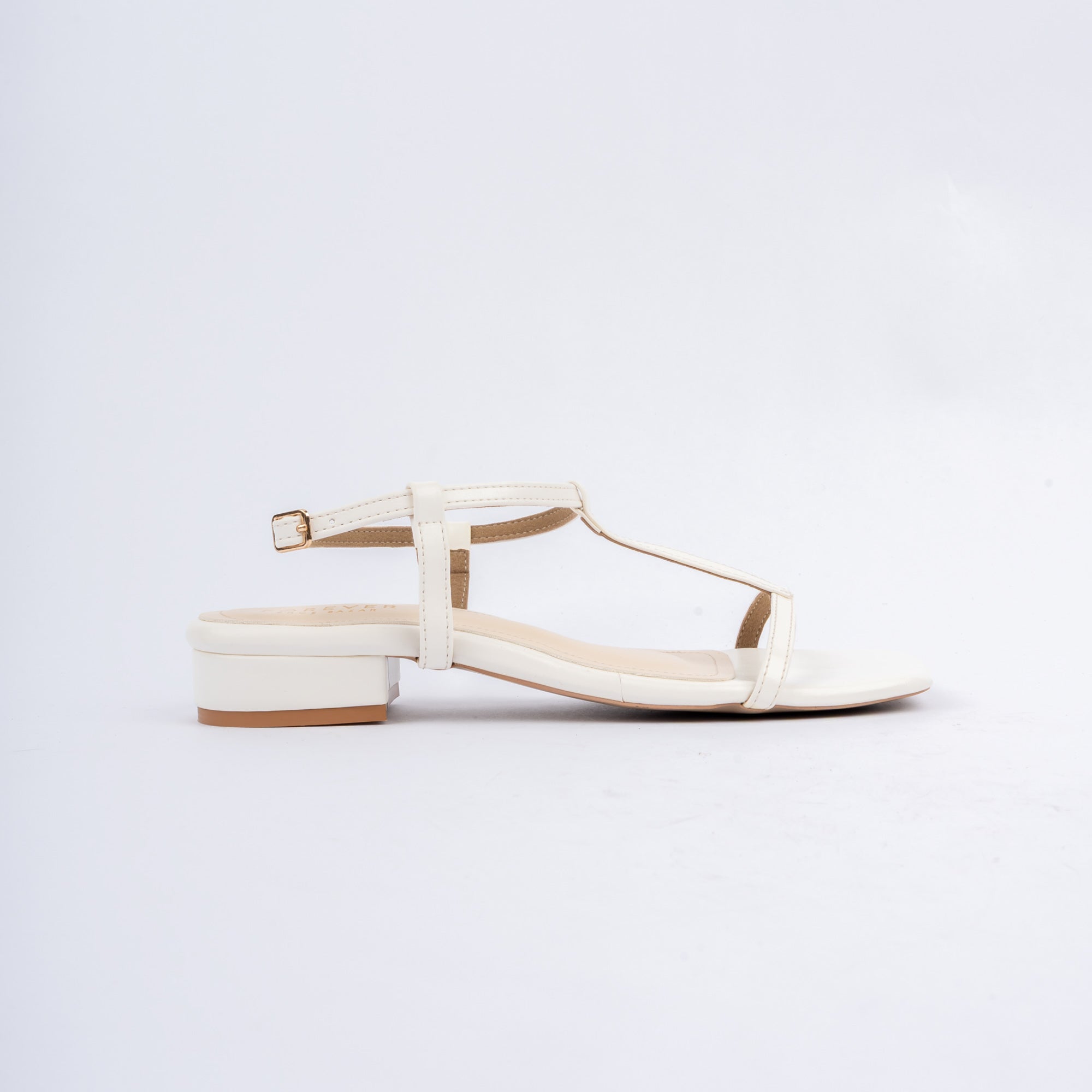 White block heel sandals for women, a slim T-bar running from a squared-off toe band up to a narrow ankle strap closed by a small gold pin buckle, over a nude footbed and a low block heel