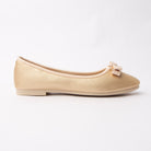 Gold bow ballerina flats for women, a soft champagne-gold metallic ballerina flat with a fine pebble grain and nude topline binding, carrying a double-loop nude grosgrain bow held by a polished gold bar