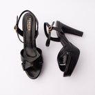Black snake print platform sandals for women, two wide glossy black snake-embossed bands cross in an X over the vamp and sit on a thick covered platform beneath the toe, with a slim gold pin buckle closing the snake-embossed ankle strap, a black-lined footbed and a tall tapering cone heel wrapped in the same black snake finish