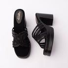 Black beaded platform mules for women, broad interlocking looped vamp built from stacked ribbons of black beadwork over sheer black mesh panels, entirely tonal so the texture reads before the shine, on an all-black footbed with a gold logo, stacked on a chunky squared block heel with a matching platform under the toe