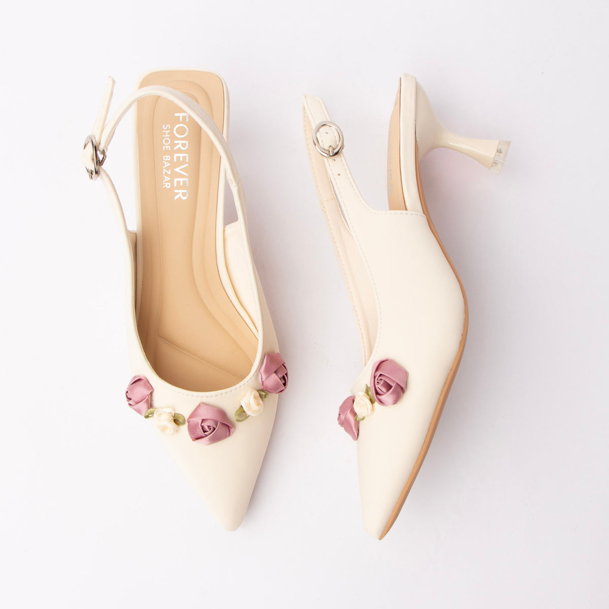 Beige rosette slingback pumps for women, an ivory pointed-toe slingback carrying a cluster of mauve and cream satin ribbon roses on green fabric leaves across the vamp, with an adjustable silver pin-buckle sling strap and a flared spool kitten heel above a padded tonal footbed