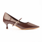 Brown mary jane kitten heels for women, a rich dark coffee-brown Mary Jane with a soft glazed sheen and a long sharply pointed toe, a narrow instep strap through a slim gold buckle, on a flared spool heel tipped with a clear block