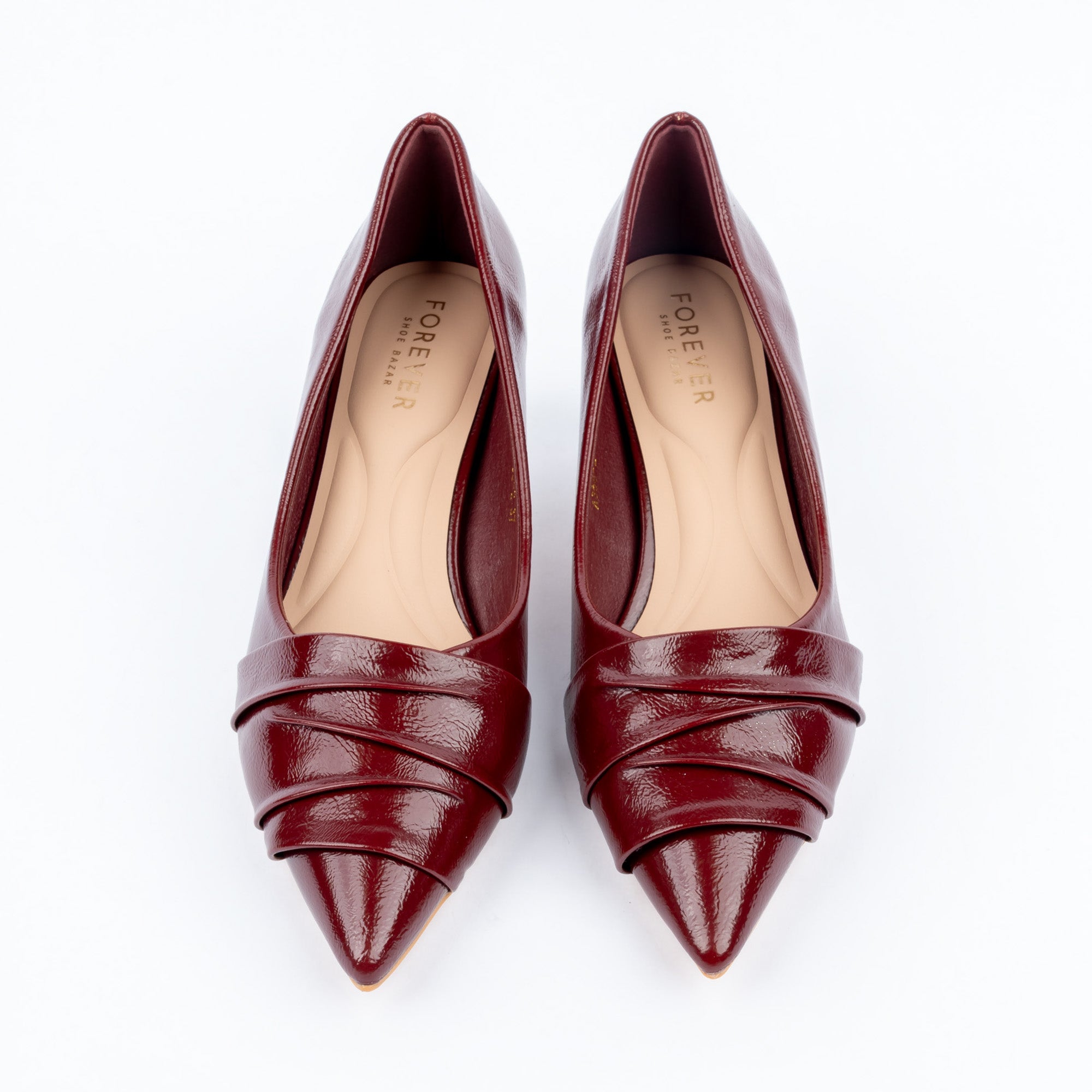 Maroon pumps for women, three overlapping pleated bands fanning diagonally across the vamp and narrowing into a sharp point, over a nude cushioned footbed with a flared kitten heel and clear tip