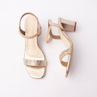 Gold embellished block heel sandals for women, a wide toe band inset with rows of small mirrored square stones above a piped sling strap that runs round the heel onto a stretch gore panel, in light champagne gold metallic pu throughout, over a cream leatherette footbed stitched around the edge and a flared block heel finished in the same gold metallic as the upper