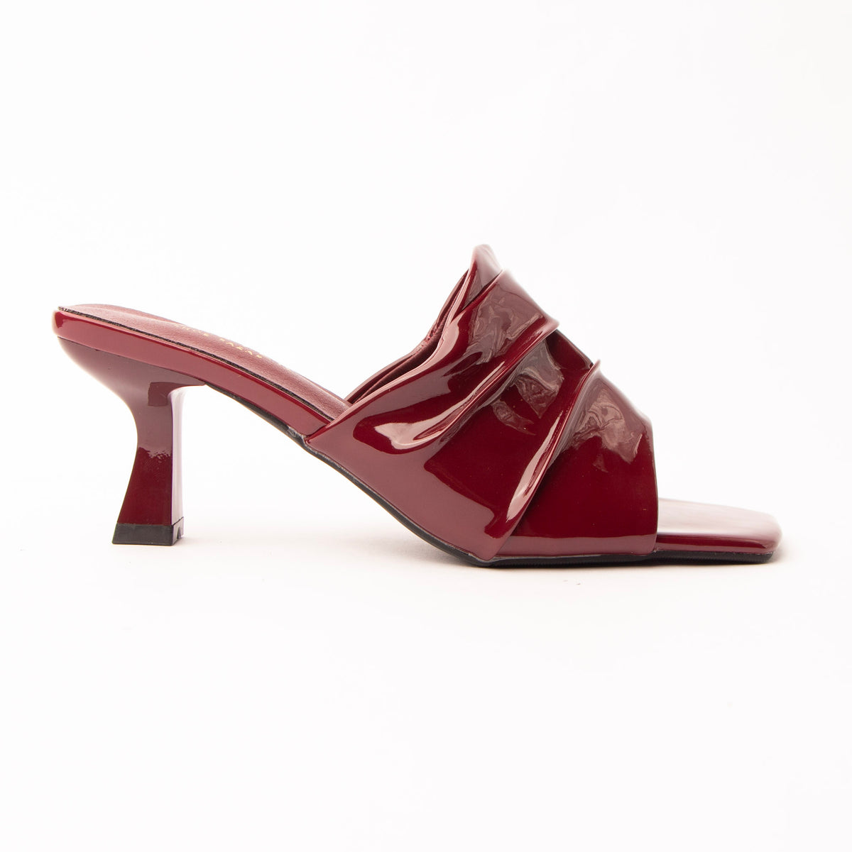Maroon patent mules for women, a deep oxblood patent mule whose gathered instep band is split into three soft tiers by two slim raised straps, the lowest running diagonally across a wide square opening, on a slim flared spool heel that lifts to cherry where the light hits