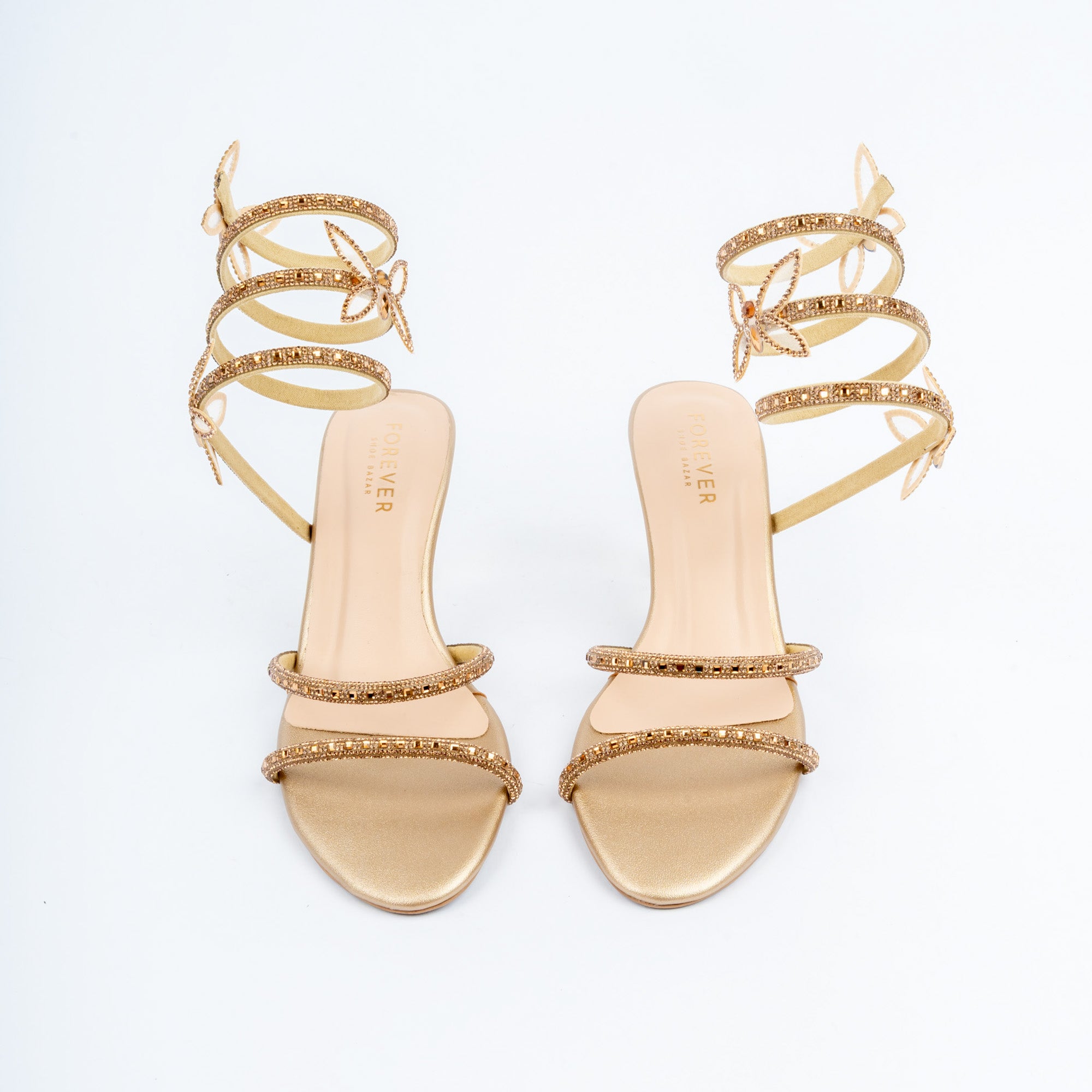 Gold block heel sandals for women, two slim crystal-set toe straps over a metallic footbed, with a flexible rhinestone coil that spirals three times round the ankle carrying three butterfly appliques