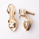 Gold snake print platform sandals for women, two light-gold snake-embossed bands cross at the vamp over a thick covered platform, with a gold pin buckle on the snake-embossed ankle strap, a pale gold footbed and a tall tapering cone heel sheathed in the same gold snake, finished on a slim tan tip