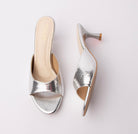 Silver snake print kitten heel mules for women, a broad silver snake-embossed vamp band is trimmed with smooth mirror-silver binding along the topline and sole edge, set over a cream footbed and a brushed silver flared hourglass kitten heel that lands on a contrast tan tip