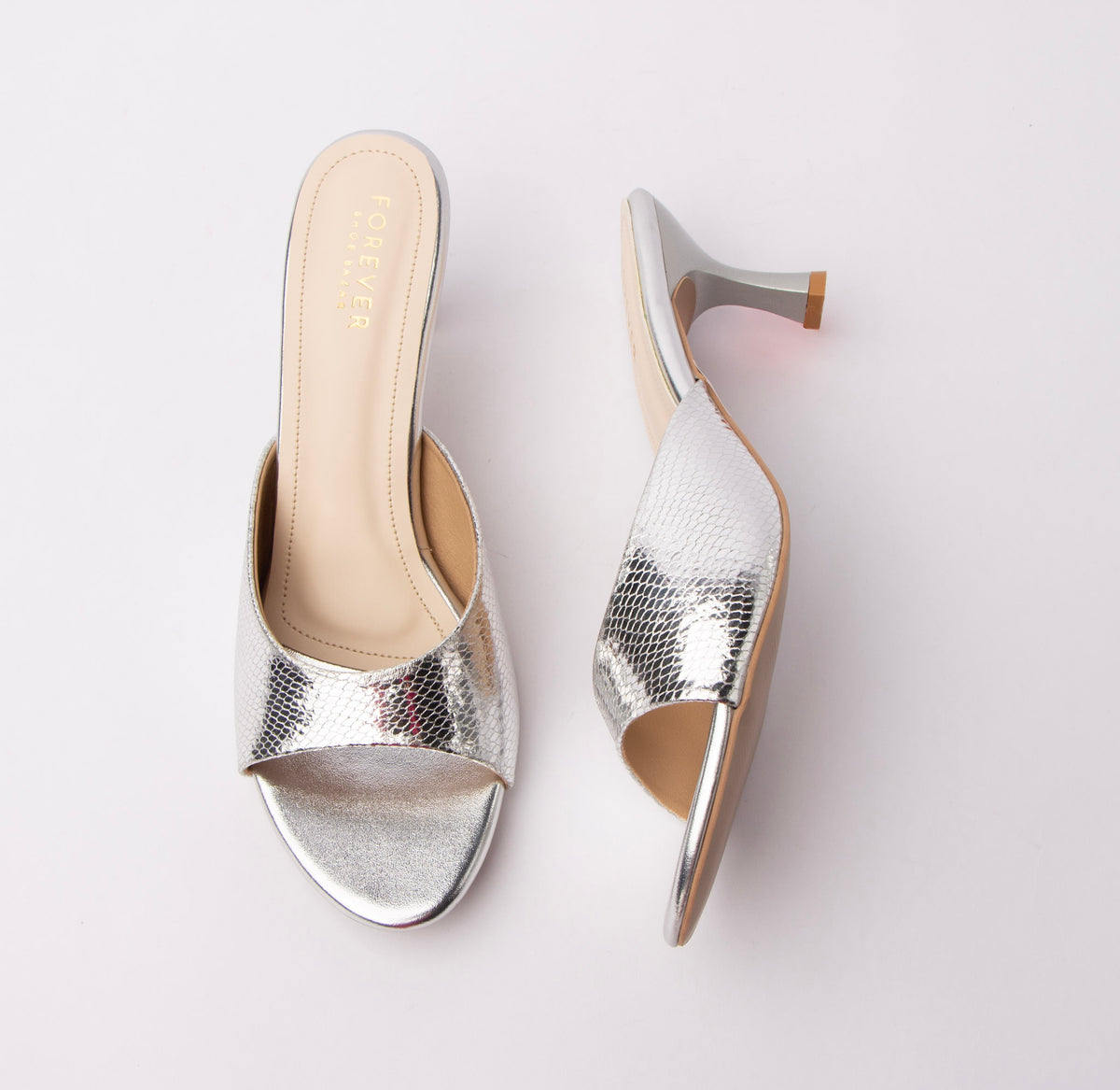 Silver snake print kitten heel mules for women, a broad silver snake-embossed vamp band is trimmed with smooth mirror-silver binding along the topline and sole edge, set over a cream footbed and a brushed silver flared hourglass kitten heel that lands on a contrast tan tip