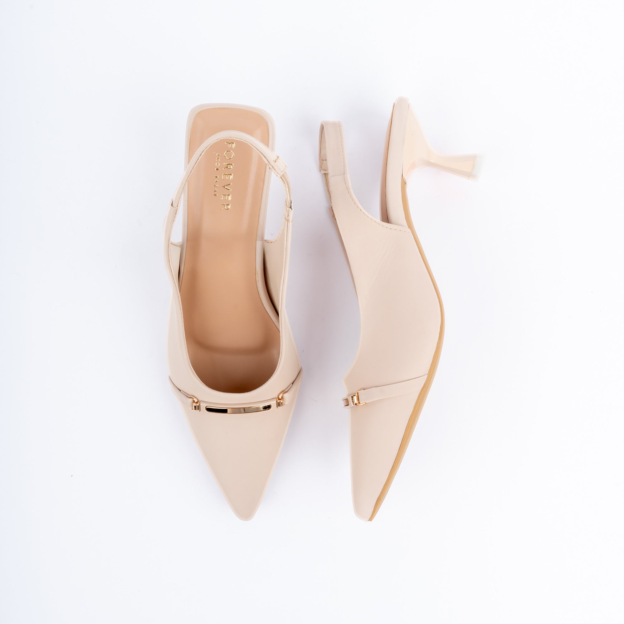 Cream pumps for women, a slim gold metal bar riding a thin strap across the pointed vamp, with a stretch slingback strap above a flared kitten heel with a clear tip