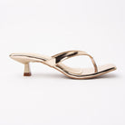 Gold toe-post kitten heel mules for women, side view of the twisted vamp band, squared-off open toe and slim kitten heel