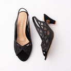 Black embellished slingback pumps for women, jet-black micro-beading traces a scalloped petal motif across sheer black mesh insets on a matte satin vamp, with laser-cut teardrops through the quarter, a gathered elastic slingback strap, a contrasting nude footbed and a flared cone kitten heel finished with a gold trim at the base