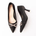 Black crystal court shoes for women, twin rows of silver rhinestones twist into a knotted loop across the vamp of a matte black satin pointed-toe court shoe, with no fastening, a nude padded footbed and a flared spool heel tipped in polished silver
