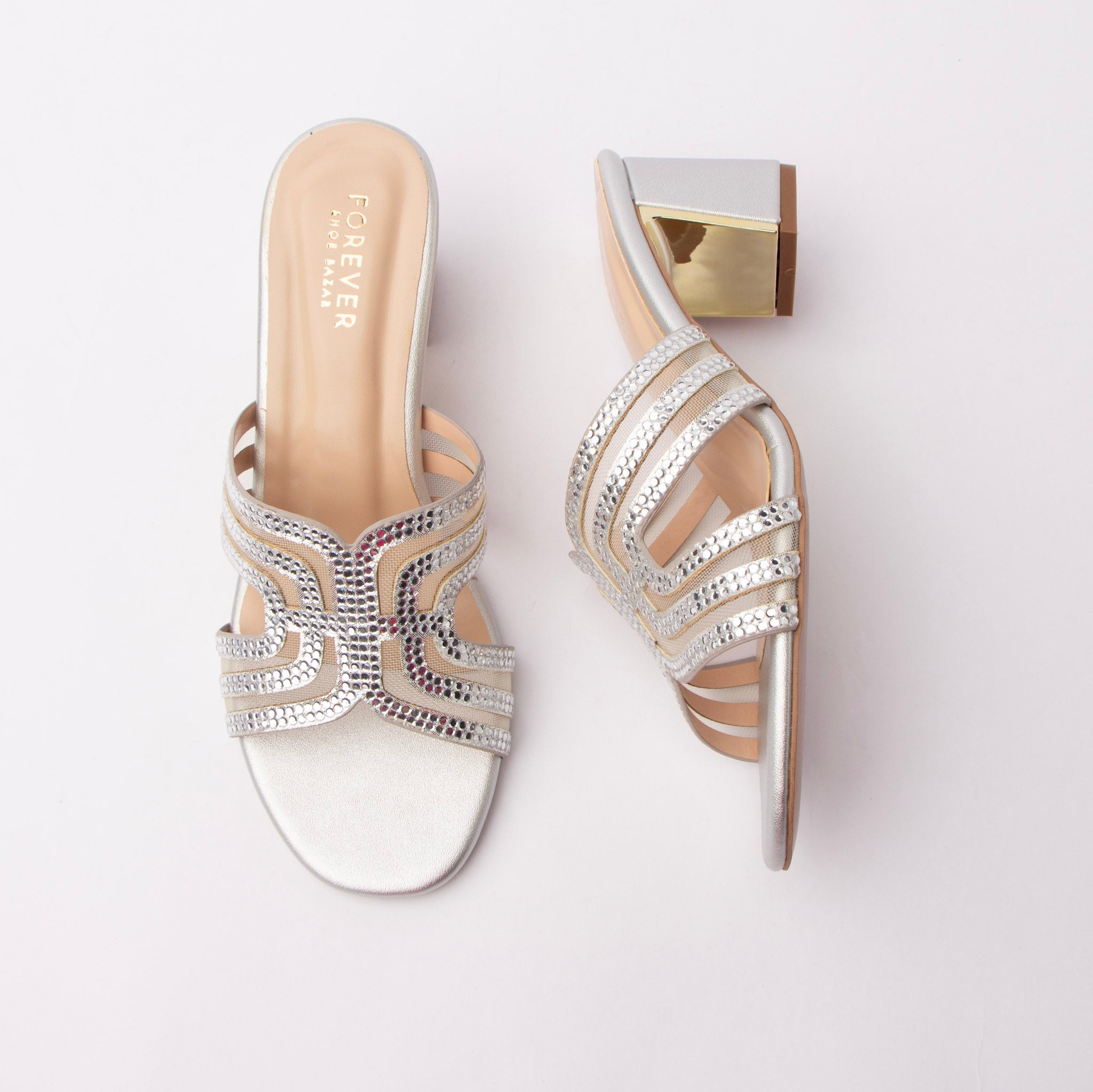 Silver block heel mules for women, crystal-studded arched bands over mesh cut-outs, a metallic footbed and a squared block heel finished with a mirror-gold metal plaque
